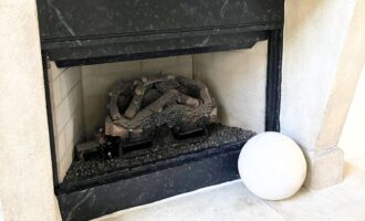 A before and after image of a damaged electric fireplace transformed into a beautiful granite masterpiece.