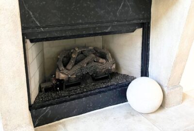 A before and after image of a damaged electric fireplace transformed into a beautiful granite masterpiece.