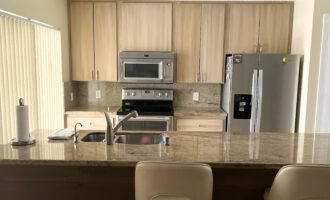 Before and after of laminate cabinets transformed with a driftwood finish, showcasing a budget-friendly DIY kitchen makeover.