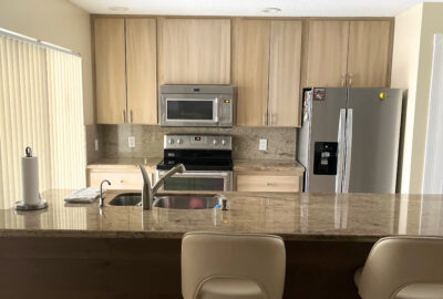 Before and after of laminate cabinets transformed with a driftwood finish, showcasing a budget-friendly DIY kitchen makeover.