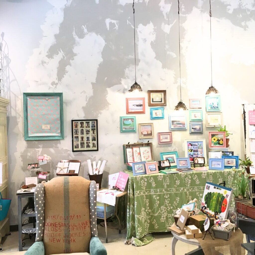 Painted art is displayed in a cozy boutique setting with styled décor and art.